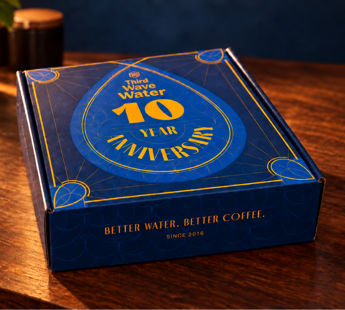A blue and gold coffee box celebrating 10 years of inversion, placed on a dark wooden table with warm lighting.