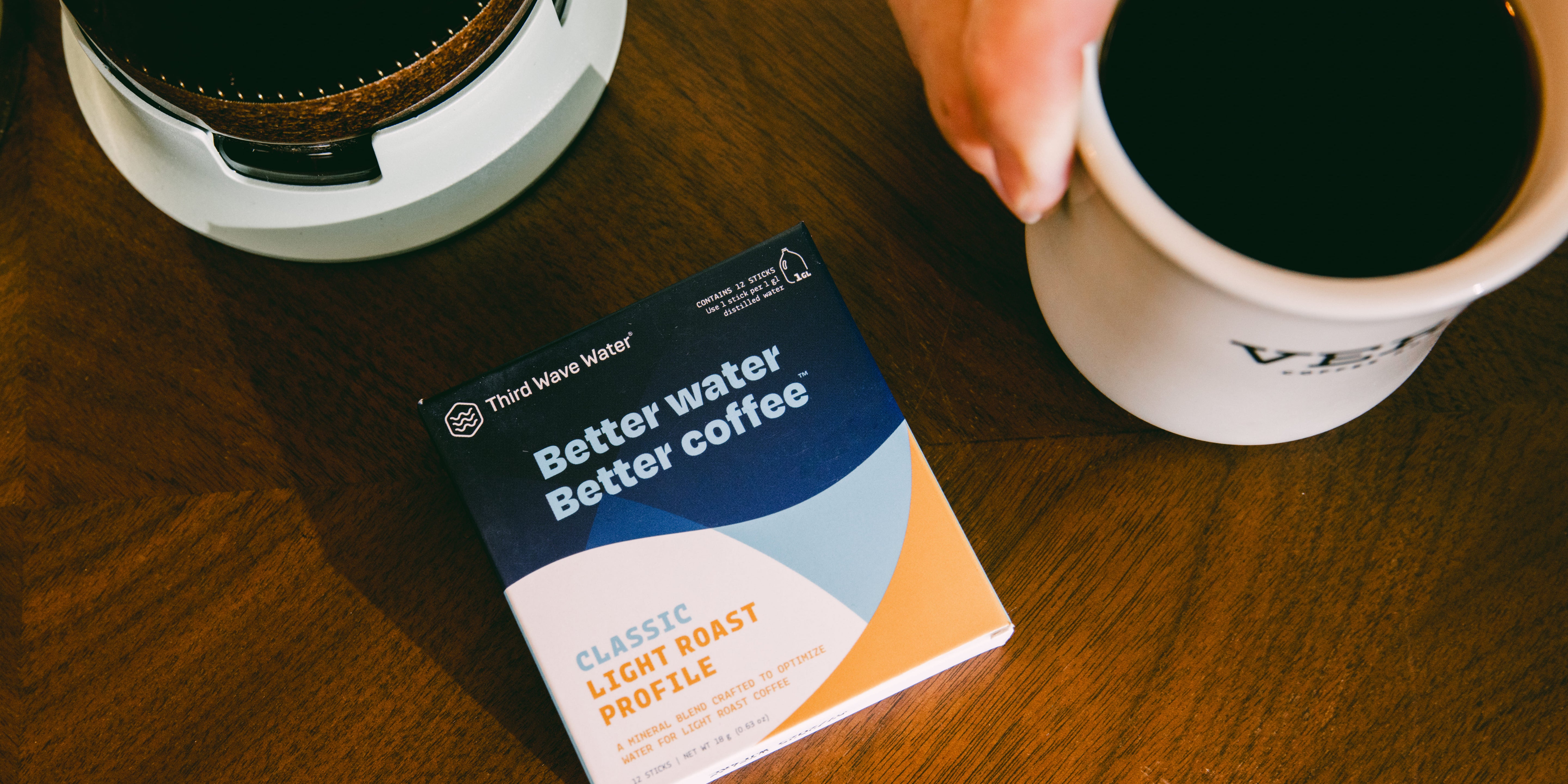 Box of Third Wave Water with a cup of coffee on a wooden table
